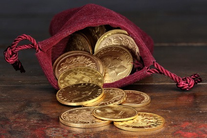 Goldmünzen verschiedener europäischer Ländern aus dem 19./20. Jahrhundert in einem Geldbeutel auf rustikalem Holztisch