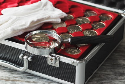 Different size collector's coins in the box and magnifying glass on the table